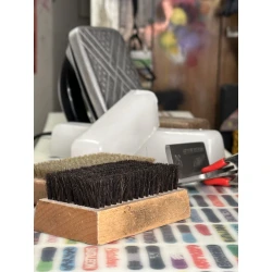 Professional snowboard hot wax service showing a waxing iron, performance wax block, and base brushes on a snowboard base